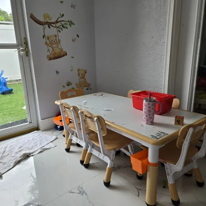 Children's activity table and chairs beside a sliding door, with teddy bear wall decals nearby