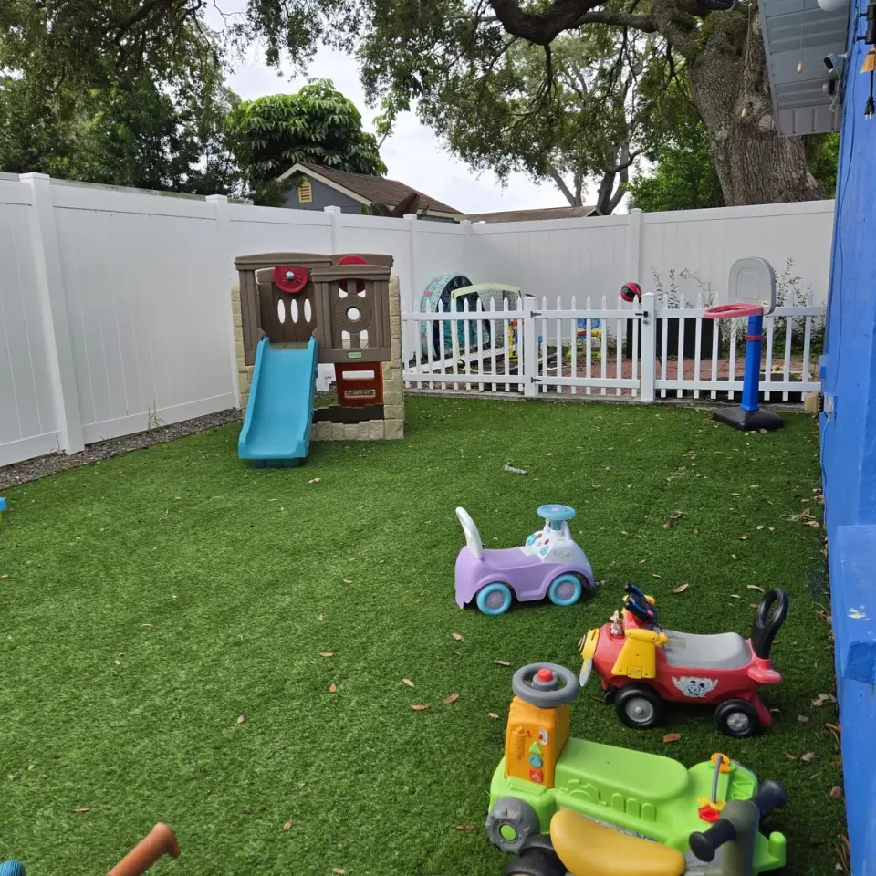 Backyard play area at Harmony House Child Care with a slide and ride-on toys