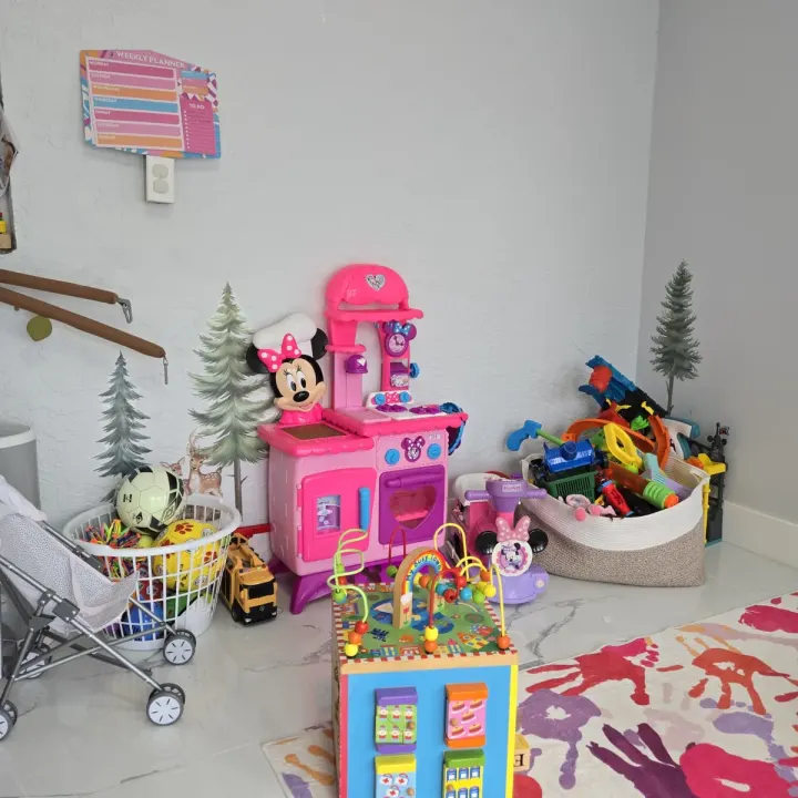 Playroom corner with a play kitchen, toy storage baskets, and a colorful handprint rug
