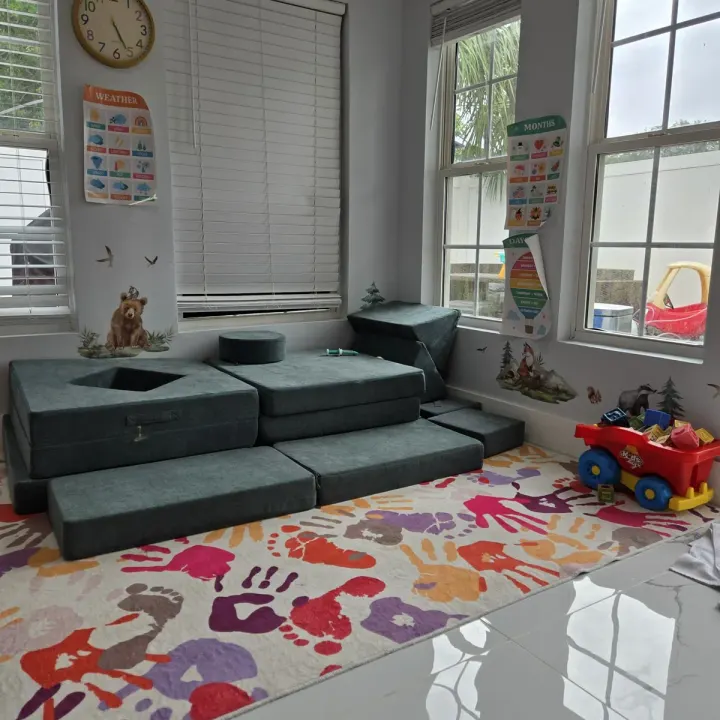 Cushioned play mats and a foam climbing set on a handprint rug in the playroom